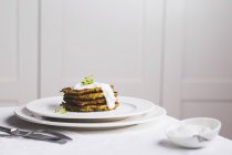 Courgette and carrot fritters on white plates over white tablecloth — Stock Photo