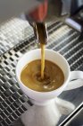 Coffee flowing from coffee machine into cup — Stock Photo
