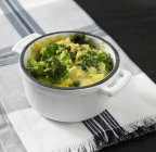 Una mini olla de estofado con verduras y polenta sobre una toalla - foto de stock