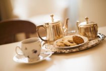 Vista inclinada do chá com biscoitos e panelas — Fotografia de Stock