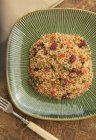Quinoa al mirtillo rosso limone in piatto verde sopra tavolo con forchetta — Foto stock