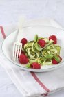 Courgettes with raspberries and pesto on white plate with fork over towel — Stock Photo