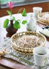 Asian buckwheat noodles in woven basket — Stock Photo
