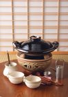 Vista de cerca del plato de estofado japonés sobre carbón con vajilla en mesa de madera - foto de stock