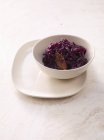 Red cabbage with apple on white plate over white surface — Stock Photo