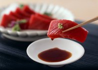Closeup view of tuna Sashimi on chopsticks — Stock Photo