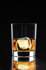 Bicchiere di whisky con un cubetto di ghiaccio — Foto stock