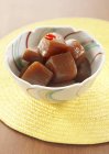Konjac simmered in spicy soy sauce in bowl over yellow mat — Stock Photo