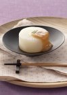 Simmered daikon radish with miso on black plate over tray — Stock Photo
