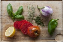 Verdure fresche, erbe aromatiche e mezzo limone su un tagliere — Foto stock