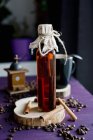 Closeup view of cinnamon syrup in bottle with cinnamon sticks and coffee beans — Stock Photo