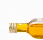 Closeup view of closed bottle of oil on white background — Stock Photo