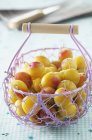 Plums in wire basket — Stock Photo