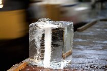 Closeup view of a large block of ice on wooden table — Stock Photo