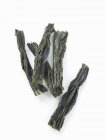 Nahaufnahme von oben von getrockneten Wakame-Algen auf weißer Oberfläche — Stockfoto