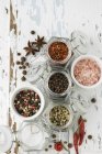 Various spices in jars and bowls  over rustic wooden surface — Stock Photo
