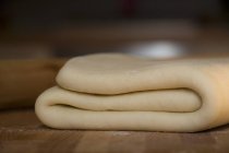 Closeup view of folded yeast dough on wooden surface — Stock Photo