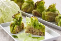 Stuffed, gratinated cabbage parcels on white plates — Stock Photo