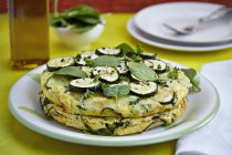 Courgette omelette with herbs on plate over table — Stock Photo