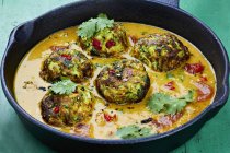 Courgette dumplings in a pepper sauce with coriander in black dish — Stock Photo