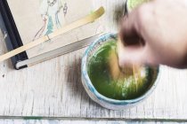 Closeup cropped view of hand mixing Matcha tea with whisk — Stock Photo