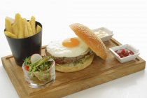 Hamburger with fried egg and chips — Stock Photo