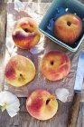 Peaches on parchment with bowl — Stock Photo
