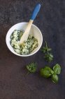 Vue surélevée du beurre à base de plantes dans un bol et des herbes — Photo de stock