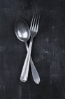 Closeup view of an old spoon and fork crossed on a black surface — Stock Photo