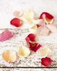 Vista ravvicinata di petali di rosa commestibili su una superficie di legno squallida — Foto stock