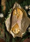 Top view of Kulebiak Polish Christmas pie in paper wrap on green branches — Stock Photo