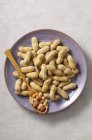 Plate of peanuts with spoon — Stock Photo