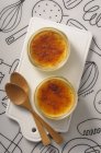 Top view of Creme brulee in two bowls with spoons on cutting board — Stock Photo