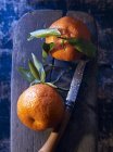 Clementine con foglie su tagliere di legno — Foto stock
