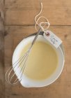 Top view of crepe batter in a bowl with a whisk and a label for a party — Stock Photo
