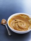 Closeup view of caramel sauce in bowl and spoon — Stock Photo