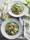 Spring risotto with green asparagus and peas in white plates over towel with forks — Stock Photo
