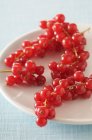 Plate of redcurrants over tablecloth — Stock Photo