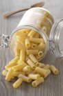Closeup view of Rigatoni tube-shaped pasta in overturned jar — Stock Photo