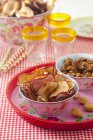Closeup view of dried apple chips and nuts in bowls on tray — Stock Photo