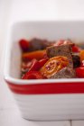 Closeup view of beef with peppers and chilli flakes in a baking dish — Stock Photo