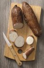 Cassava root, partially sliced, on a chopping board with a knife — Stock Photo