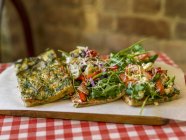 Focaccia mit Kräutern, Gemüse und Rucola über Holztisch — Stockfoto