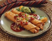Closeup view of chicken Taquitos with sauces on a plate — Stock Photo