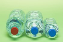 Vista de cerca de tres botellas de plástico de agua en la superficie verde - foto de stock