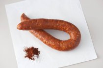 Closeup view of Linguica sausage on white paper with Paprika and salt — Stock Photo