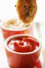 Dipping chicken nugget into ketchup — Stock Photo