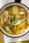 Курячий суп з овочами в каструлі над рушником — стокове фото