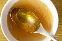 Close-up vista superior da sopa de frango transparente na tigela com colher — Fotografia de Stock