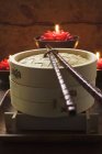 Closeup view of bamboo steamer in front of burning candles — Stock Photo